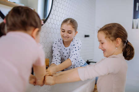 Three little sisters washing hands in bathroom, morning routine concept.