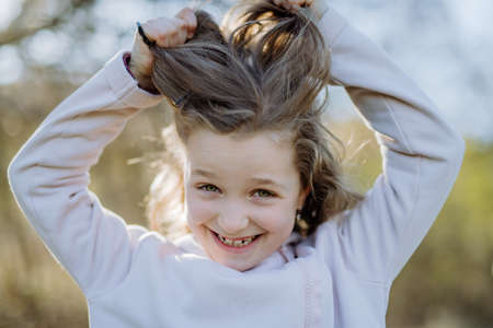 Funny portrait of pretty child girl standing in summer park looking in camera smiling happily.の写真素材