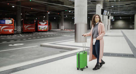 Woman traveler tourist waiting with luggage at bus station.