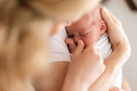 Unrecognizable mother holding her newborn son at home, close-up