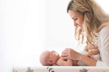 Happy mother bonding with her newborn son who is lying on changing mat at home.の写真素材