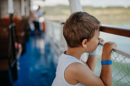 Little curious boy looking at water from motor boat.の写真素材
