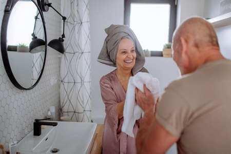 Senior couple in bathroom, brushing teeth and washing, morning routine concept.