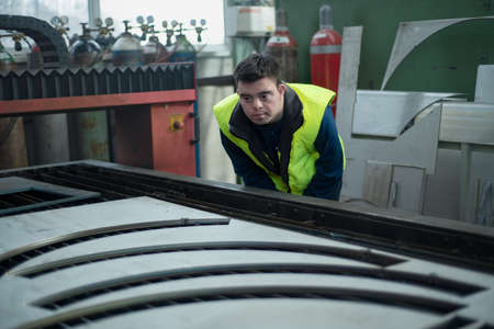 Young man with Down syndrome working in industrial factory, social integration concept.