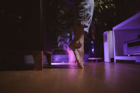 Close up focus on young female feet standing barefoot on tip toes on wooden floor at home.の写真素材