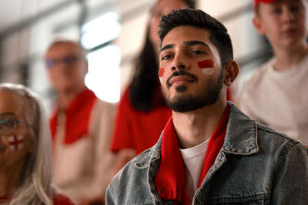 Excited football fans supproting Monaco national team in live soccer match at stadium.