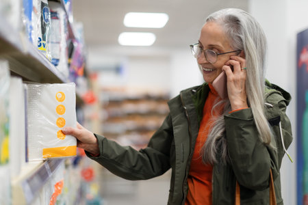 Elder woman buying drugstore goods in supermarket and phoneing.の写真素材
