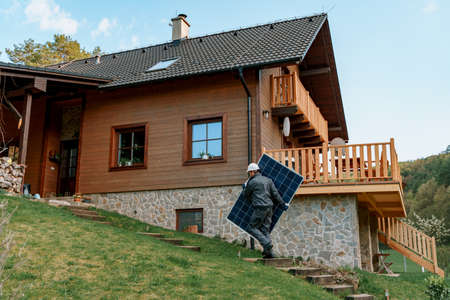 Man worker carrying solar panel for installing solar modul system on house.の写真素材