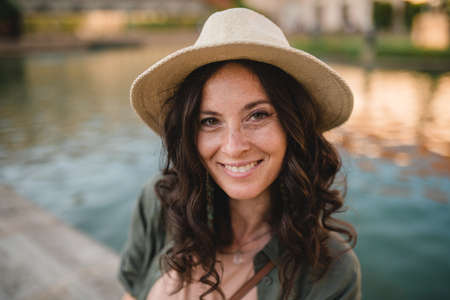 Woman candid portrait from park. Young urban female tourist smiling looking at camera.
