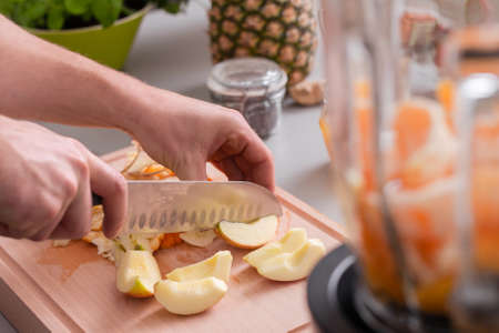 Unrecognizable man cutting apples on chopping board.の写真素材