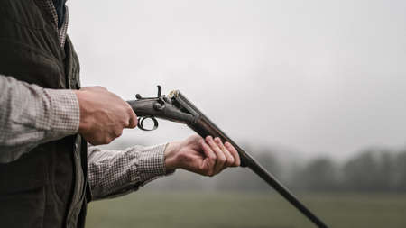 Close-up of hunter man charges the cartridge on rifle gun in forest.の写真素材