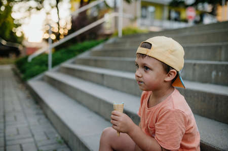Little cute boy with ice cream outdoors in summerの写真素材