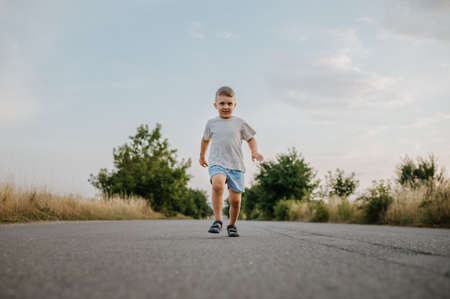 Little boy is running on road in summerの写真素材