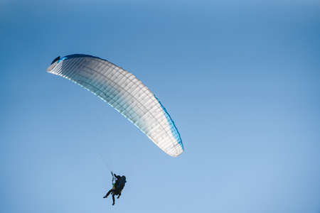 Paraglider in the blue sky. The sportsman flying on a paraglider.の写真素材