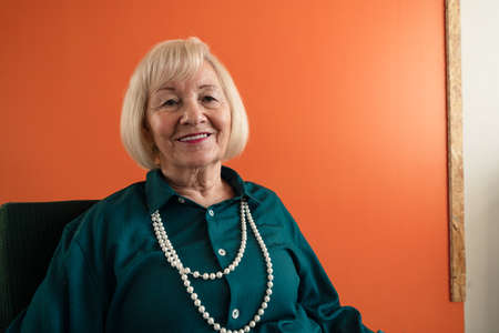 Smiling elegant elderly woman sitting in armchair