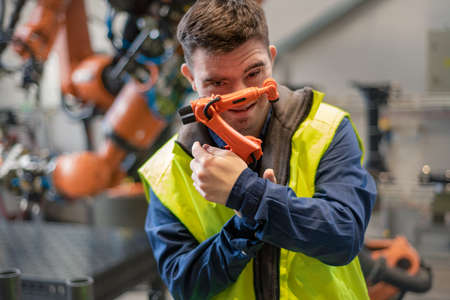 Young man with Down syndrome looking at blueprints when working in industrial factory, social...