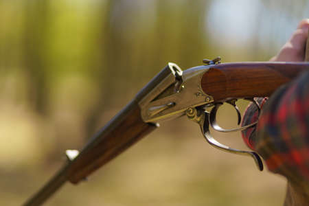 Close-up of hunter man charges the cartridge on rifle gun in forest.の写真素材