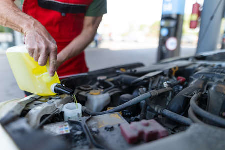 Car mechanic replacing and pouring oil into engine at maintenance repair service stationの写真素材