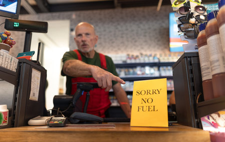Senior employee pointing on no fuel sign on petrol station due to economic crisiesの写真素材