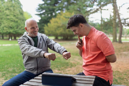 Happy senior father with his adult son with Down syndrome playing and sitting in park.の写真素材
