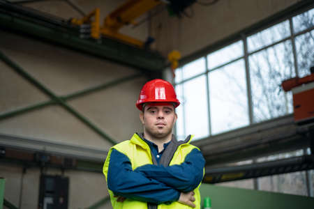 Young man with Down syndrome working in industrial factory, social integration concept.