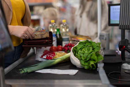 Close-up of woman giving money at the cash desk in supermarketの写真素材