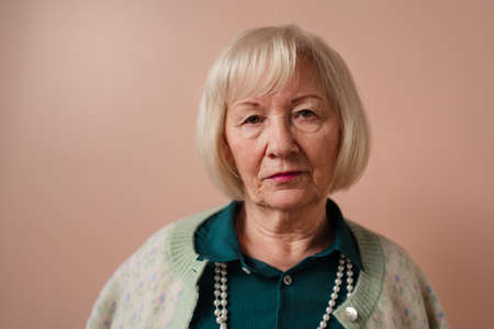 Senior woman sitting on sofa and reading book at home