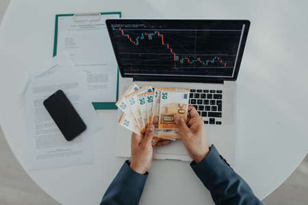 Businessman man counting euro money working on computer at office desk, inflation concept., top...