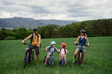 Portrait of young family with little children preapring for bike ride, standing with bicycles in nature.の写真素材