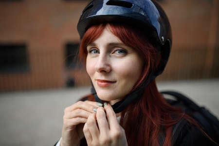 Portrait of businesswoman commuter on the way to work putting on cycling helmet, sustainable lifestyle concept.の写真素材