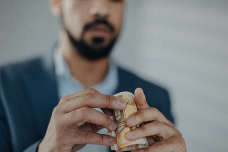 Depressed businessman man looking through a tube of money, inflation concept.の写真素材