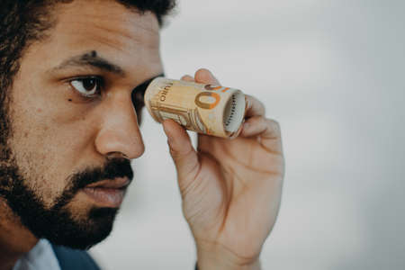 Depressed businessman man holding banknotes in a tube, inflation concept.の写真素材