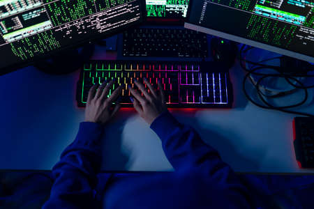Close-up of woman hacker hands at keyboard computer in the dark room at night, cyberwar concept. Top view.の写真素材