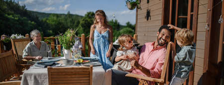 Three generation family having fun at barbecue party dinner on patio, people sitting at table on...
