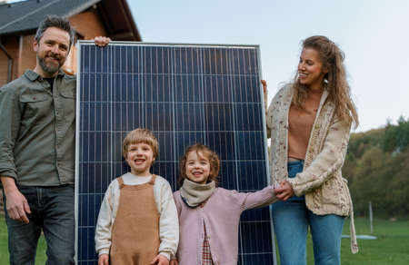 Happy family near their house with solar panels. Alternative energy sourceの写真素材