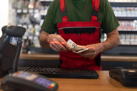 Employee taking cash payment from costumer in gas station, close-up