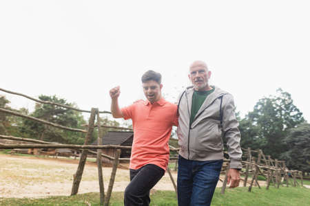 Happy senior father with his young son with Down syndrome walking in park together.の写真素材