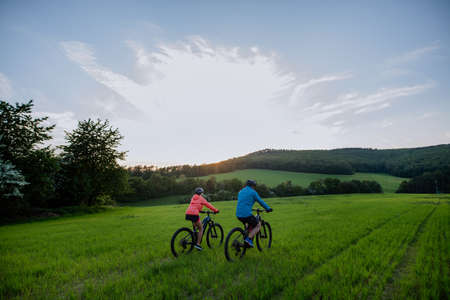 Active senior couple riding electric bicycles on trail at summer park, healthy lifestyle concept....