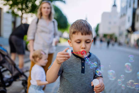 Little boy blowing bubbles in city street in summer.の写真素材