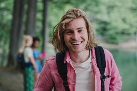 Portrait of young man with friends at background on a hiking or camping trip in the mountains in summer.の写真素材