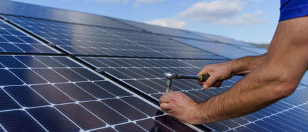 Man worker installing solar photovoltaic panels on roof, alternative energy concept.Close up hands...