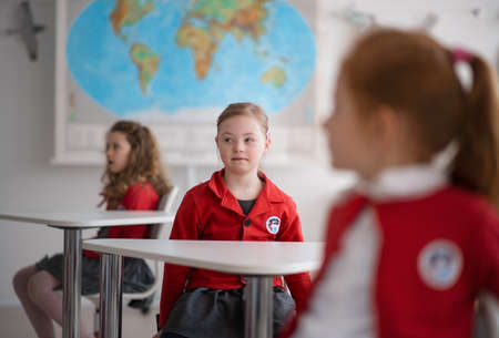 Down syndrome schoolgirl paing attention in class at school, integration concept.の写真素材