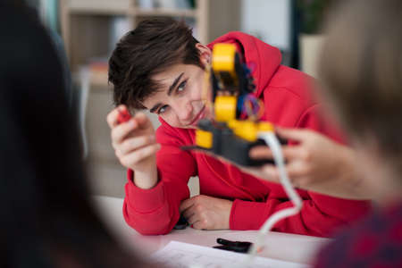 Group of students building and programming electric toys and robots at robotics classroom