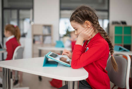Schoolgirl using digital tablet during lesson in classroom at primary school.の写真素材