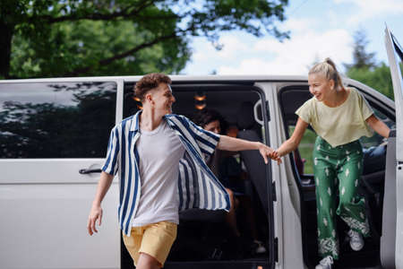 Young friends travelling together by car,getting out from car - summer vacation, holidays, travel,...