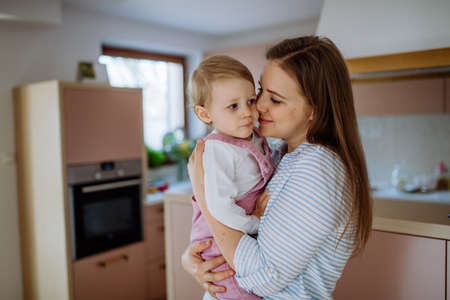 Young mother hugging her little daughter at home, lifting her up.の写真素材