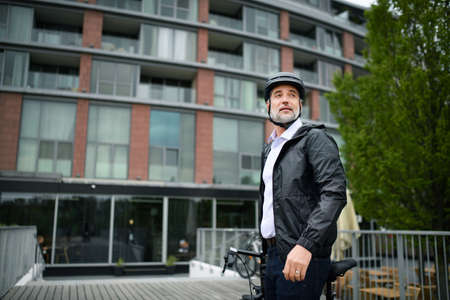 Businessman commuter on the way to work, pushing bike, sustainable lifestyle concept.