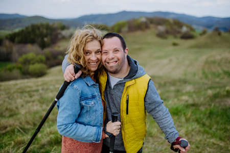 Portrait of happy young man with Down syndrome with his mother hiking together in nature.