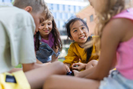 Happy kids playing and talking together in city park, during summer day.の写真素材