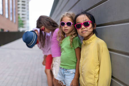 Happy friends posing together in city, standing in front of concrete wall and looking at camera.の写真素材
